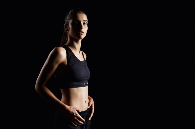  young beautiful sportive girl posing over dark wall.