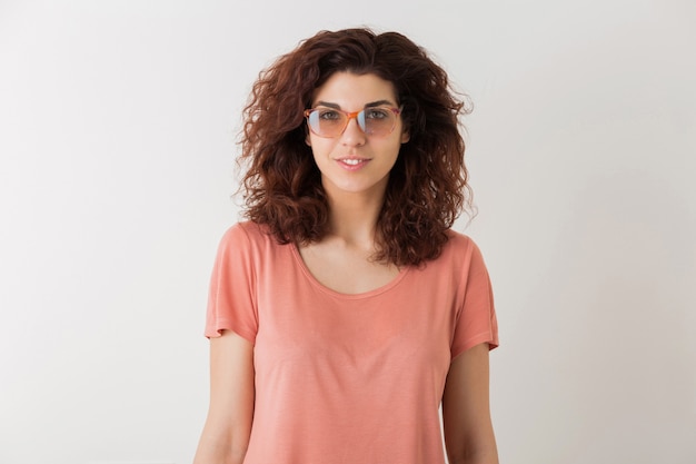 Free photo young beautiful stylish woman in glasses, curly hair, smiling, positive emotion, happy, isolated on white background, pink t-shirt, hipster style, student, looking in camera, natural look