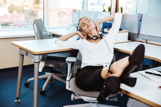 Free photo young beautiful successful businesswoman resting, relaxing at workplace, over office