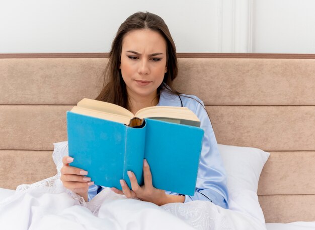 Young beautiful woman in blue pajamas laying on bed