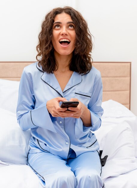 Young beautiful woman in blue pajamas laying on bed