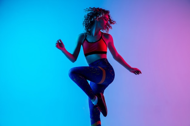 Free photo young beautiful woman in bright sportwear isolated on gradient pink-blue background in neon light.