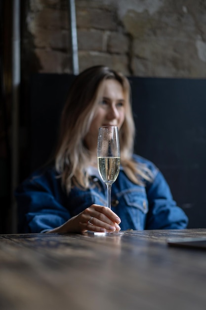 Free photo young beautiful woman in a cafe, a woman drinking champagne in a cafe and talking.