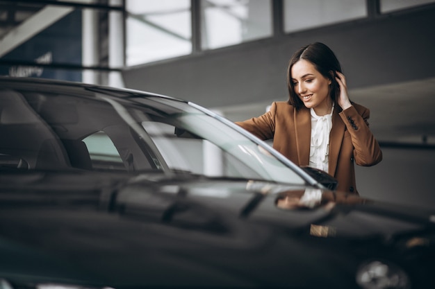 Young beautiful woman choosing car in a car showroom