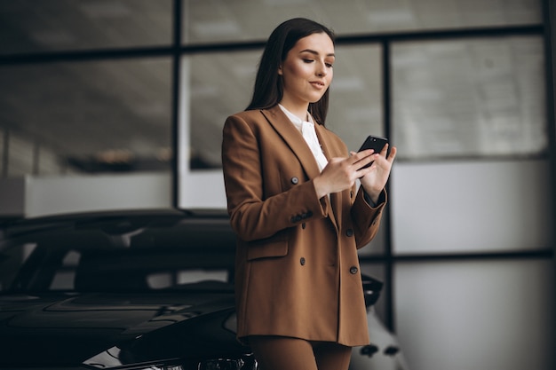 Young beautiful woman choosing car in a car showroom