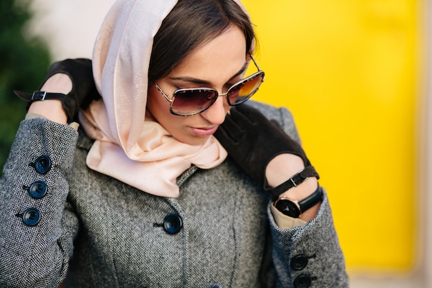 Free photo young beautiful woman in a coat sitting on a bench in the park