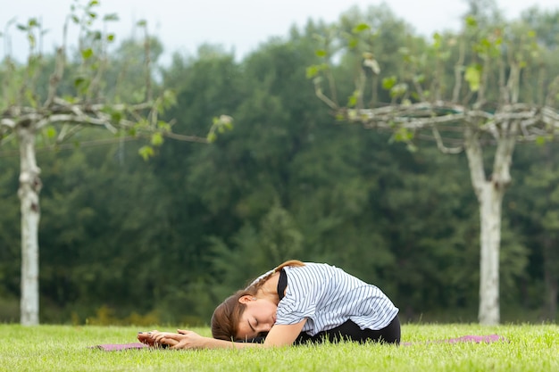 Young beautiful woman doing yoga exercise outdoors