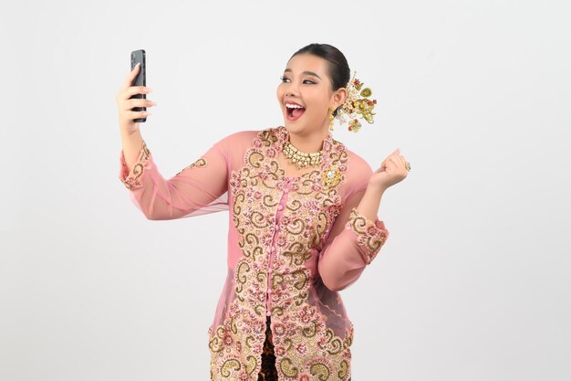 Young beautiful woman dress up in local culture in southern region pose with smartphone