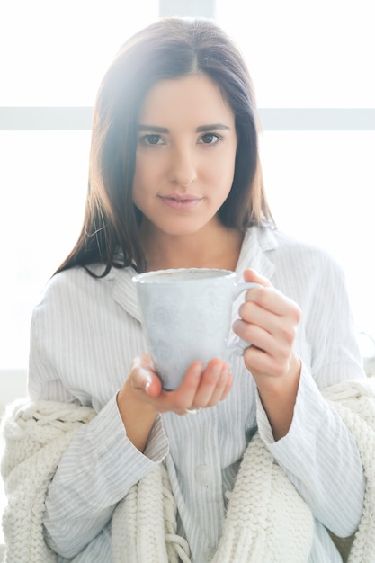 Young beautiful woman drinking a hot drink in the kitchen