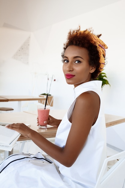 Young beautiful woman drinking smoothie smiling resting in cafe