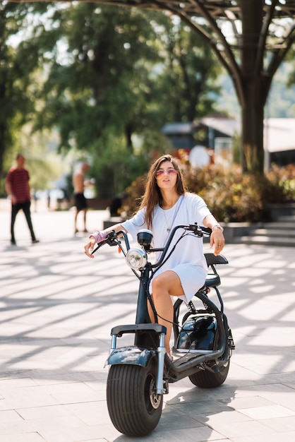 Young beautiful woman and an electric scooter ecological transport