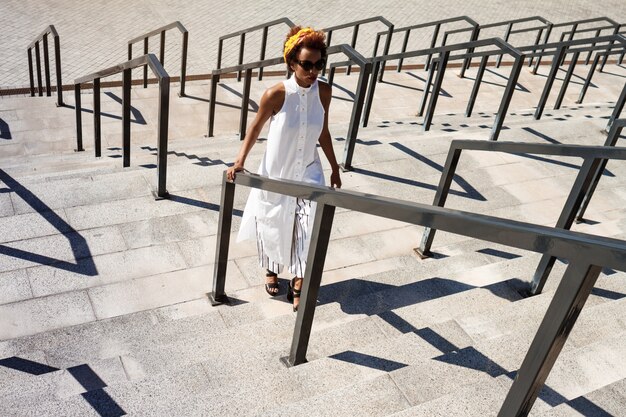 Young beautiful woman going up stairs walking down city