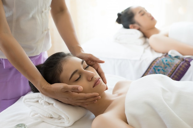 Young beautiful woman having face massage relaxing in spa.