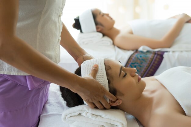 Young beautiful woman having face massage relaxing in spa.