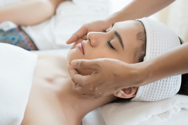 Young beautiful woman having face massage relaxing in spa.