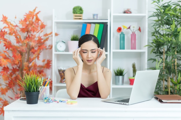 Young beautiful woman having headache working on computer at home