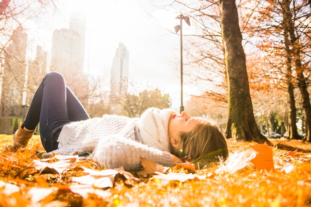 Free photo young beautiful woman laying in shiny park