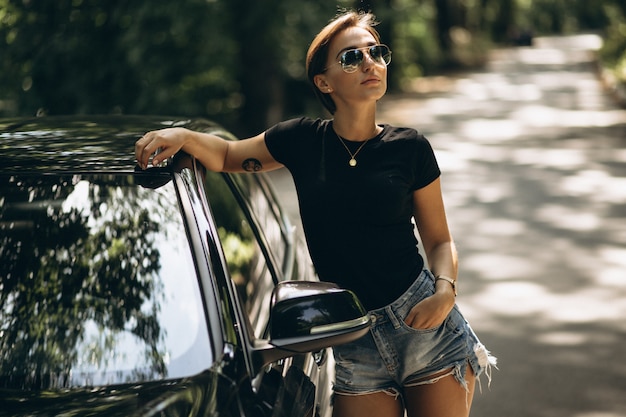 Free photo young beautiful woman leaning on car