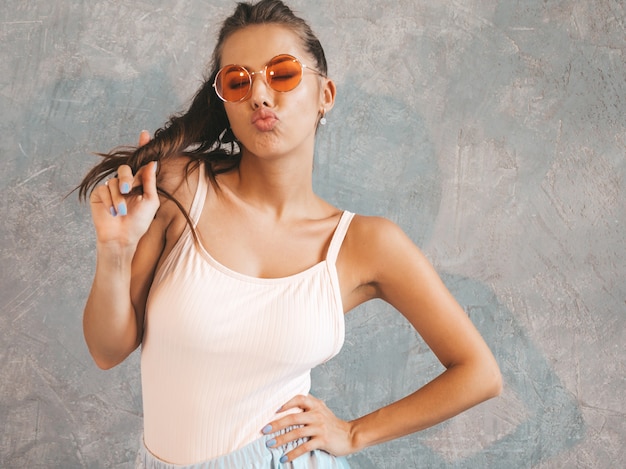 Young beautiful woman looking . Trendy girl in casual summer dress and sunglasses.   and giving kiss