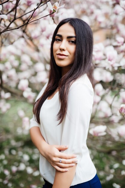 Young beautiful woman near magnolia blooming tree. Cute young woman near magnolia tree