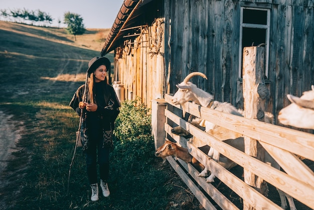 Free photo a young beautiful woman near a pen with goats