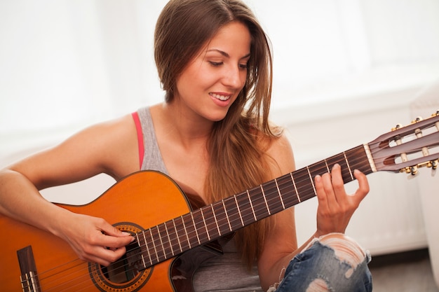 Young beautiful woman playing guitar 