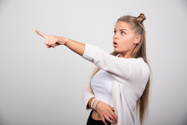 Young beautiful woman pointing with hand and finger to the side .