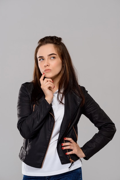 Young beautiful woman posing, thinking over purple wall