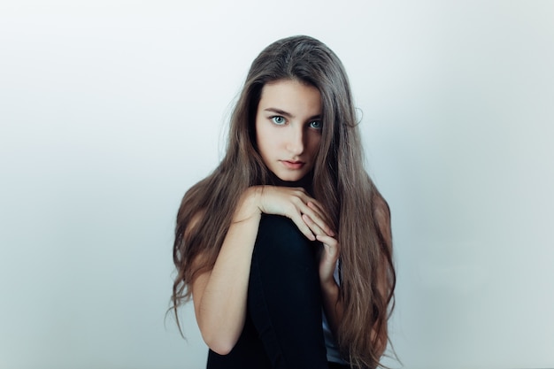 Young beautiful woman posing on a white wall