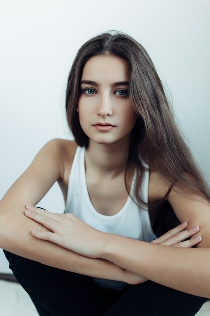 Young beautiful woman posing on a white wall