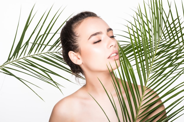 Young beautiful woman posing with green palm leaves