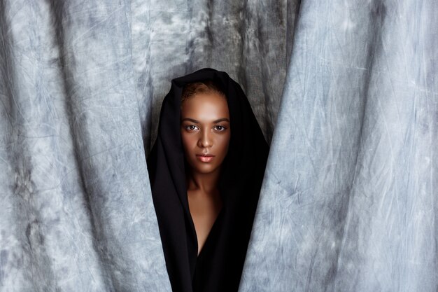 Young beautiful woman posing, wrapping up  in grey cloth