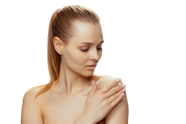 Free Photo young beautiful woman putting moisturizing cream on body isolated over white studio background