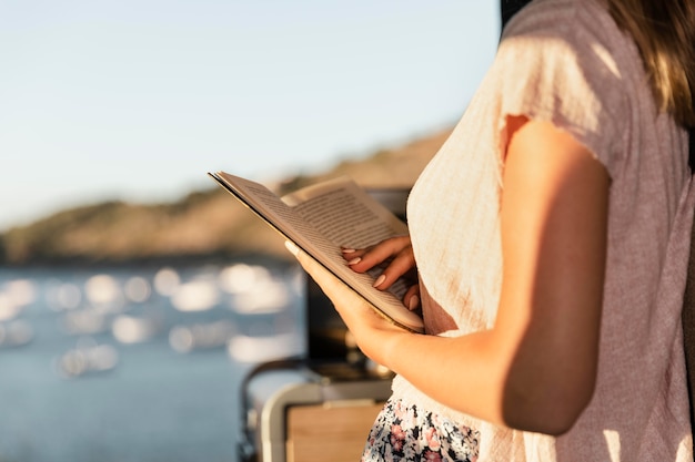 Young beautiful woman reading by the lake