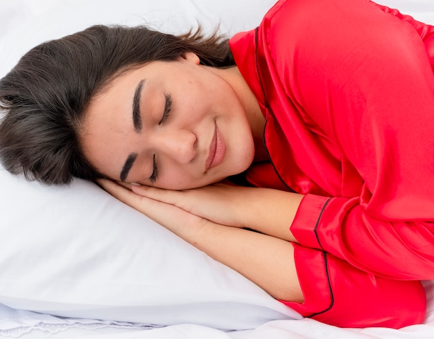 Young beautiful woman in red pajamas relaxing in bed