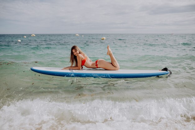 Young beautiful woman relaxing in the sea on a SUP board.