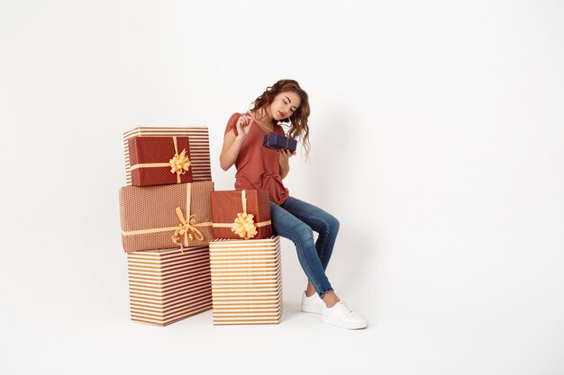 Free photo young beautiful woman sitting on big gift box opening smaller one