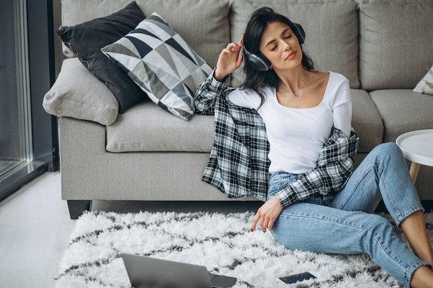 Free photo young beautiful woman sitting home working on laptop in earphones