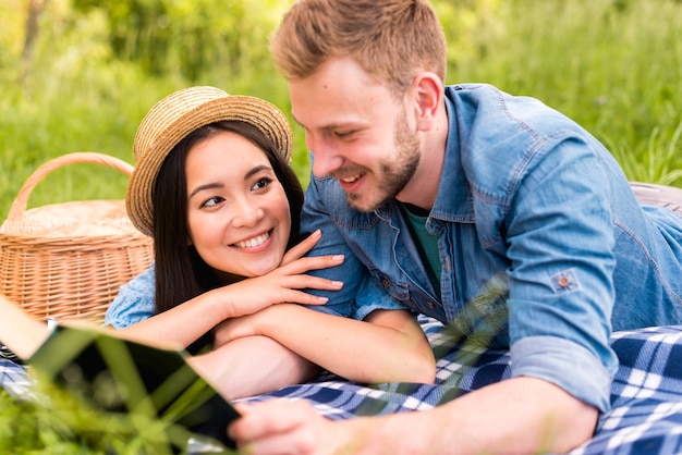 Young beautiful woman smiling at reading man in countryside