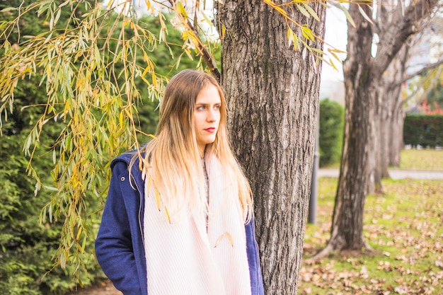 Free photo young beautiful woman standing back to autumn park