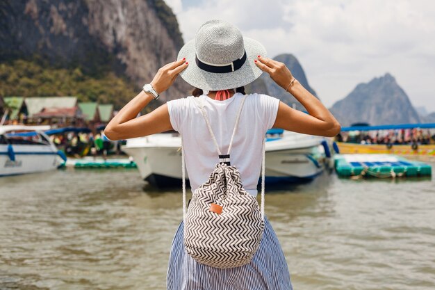 Young beautiful woman in summer fashion outfit, casual style, traveling with backpack, hat, sunglasses, vacation in thailand, asia