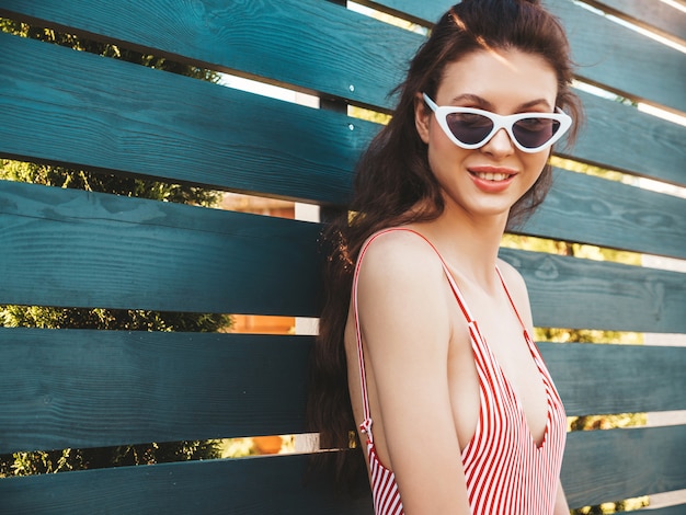 Free photo young beautiful woman in swimwear and sunglasses posing in the street