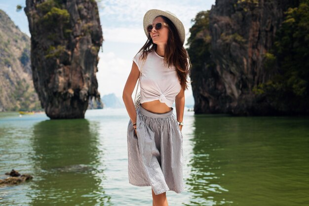 Young beautiful woman traveling in thailand, summer vacation, casual style, sunglasses, hat, cotton skirt, t-shirt, smiling, happy, adventures