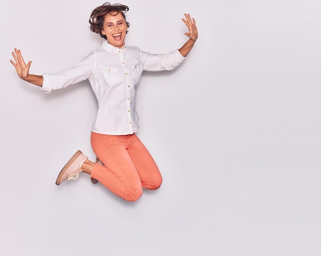 Free Photo young beautiful woman wearing casual clothes smiling happy jumping with smile on face and arms opened over isolated white background