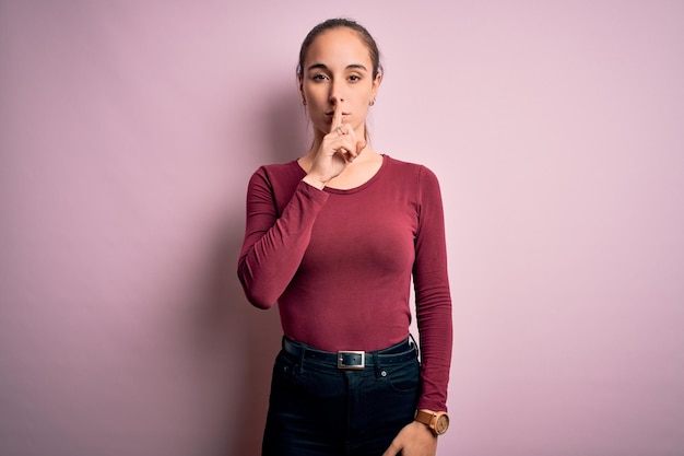 Free photo young beautiful woman wearing casual tshirt standing over isolated pink background asking to be quiet with finger on lips silence and secret concept