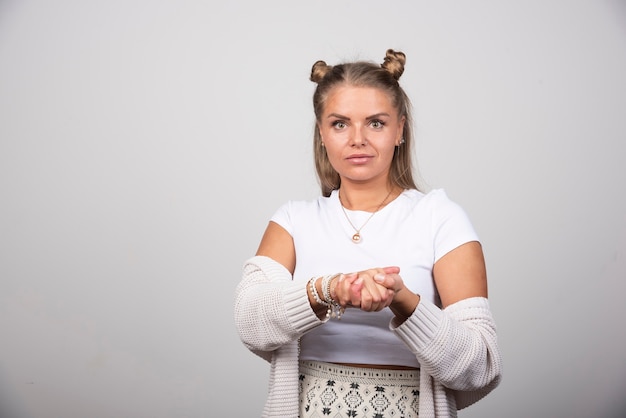 Young beautiful woman in white outfit holding her hands.