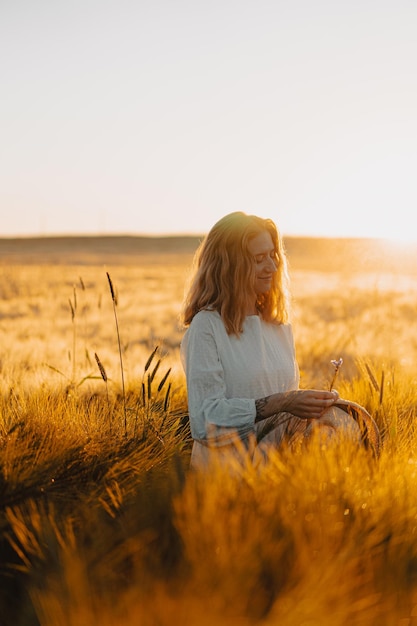 young beautiful woman with long blond hair in a white dress on a wheat field in the early morning at sunrise. Summer is the time for dreamers, flying hair, a woman running across the field in the rays