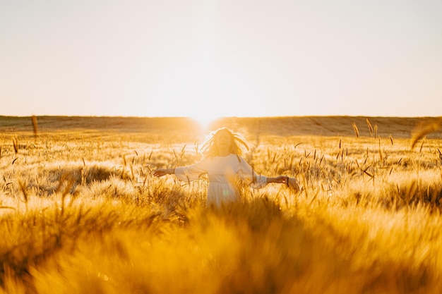 Free Photo young beautiful woman with long blond hair in a white dress on a wheat field in the early morning at sunrise. summer is the time for dreamers, flying hair, a woman running across the field in the rays