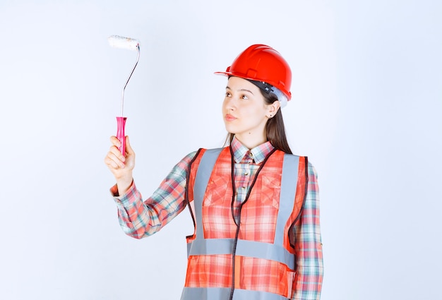 Young beautiful woman with a paint roller to paint wall repair. 