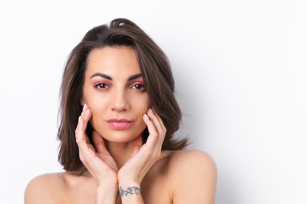 Young beautiful woman with perfect skin bright spring pink makeup and naked shoulders on a white background